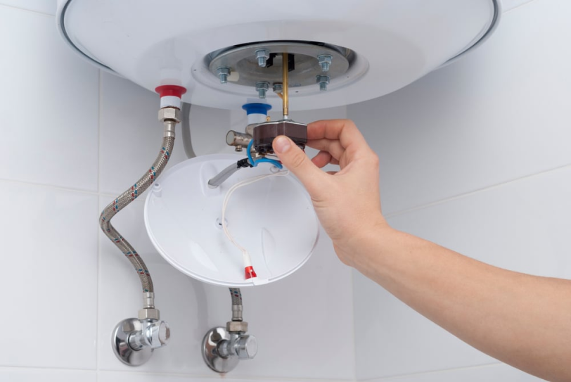 Técnico ajustando la válvula inferior de un termo eléctrico durante una reparación en Barcelona